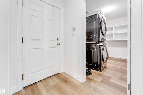 Laundry room with light wood finished floors, stacked washer and dryer, and a textured ceiling - 107 9760 176 St, Edmonton, AB - Indoor Photo Showing Laundry Room