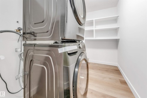 Laundry area with light wood finished floors and stacked washing machine and dryer - 107 9760 176 St, Edmonton, AB - Indoor Photo Showing Laundry Room