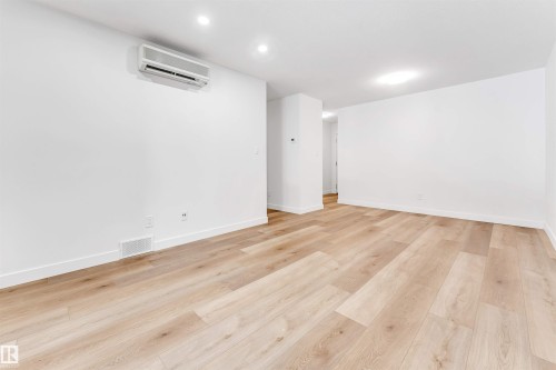 Empty room featuring light wood-type flooring and a wall mounted mini split - 107 9760 176 St, Edmonton, AB - Indoor Photo Showing Other Room