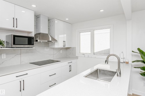 Kitchen with white cabinets, tasteful backsplash, stainless steel microwave, light stone counters, and recessed lighting - 13520 113A Street, Edmonton, AB - Indoor Photo Showing Kitchen With Upgraded Kitchen