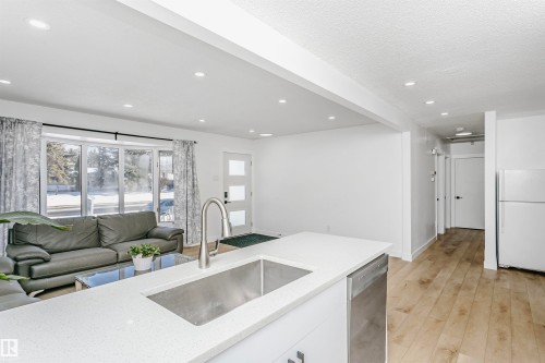 Kitchen featuring freestanding refrigerator, open floor plan, white cabinets, light stone countertops, and light wood-style flooring - 13520 113A Street, Edmonton, AB - Indoor