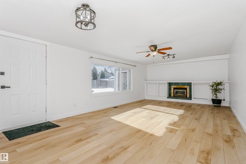Unfurnished living room with light wood-style floors, a ceiling fan, and a fireplace - 13520 113A Street, Edmonton, AB - Indoor Photo Showing Other Room With Fireplace