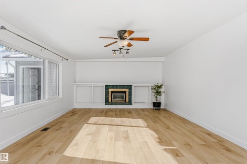 Unfurnished living room with a ceiling fan, light wood-style flooring, and a fireplace - 13520 113A Street, Edmonton, AB - Indoor With Fireplace