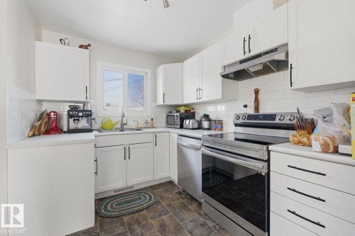 Kitchen with stainless steel appliances, light countertops, white cabinetry, and stone finish floors - 11332 134 Avenue, Edmonton, AB - Indoor Photo Showing Kitchen