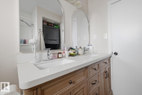 Bathroom featuring double vanity and stacked washer and clothes dryer - 11332 134 Avenue, Edmonton, AB - Indoor Photo Showing Bathroom
