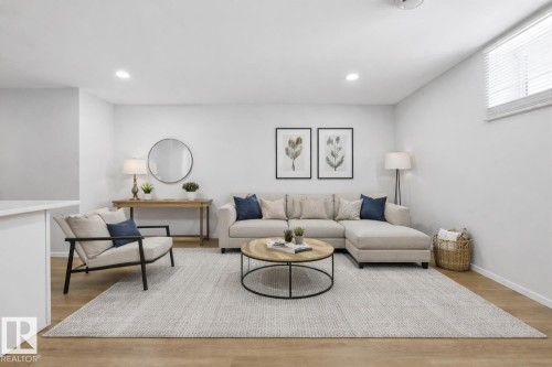 The living area features light-colored walls and wood flooring, enhanced by recessed lighting - 11332 134 Avenue, Edmonton, AB - Indoor Photo Showing Living Room