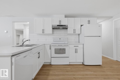 The kitchen features white cabinetry, a white subway tile backsplash, and light-colored countertops - 11332 134 Avenue, Edmonton, AB - Indoor Photo Showing Kitchen With Double Sink