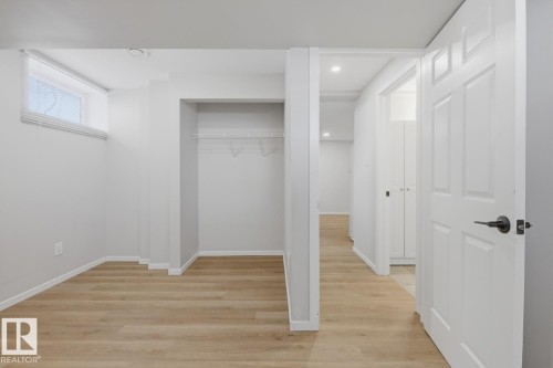 This area features light wood-style flooring, a window with blinds, and an open closet space with a clothes rod and shelf - 11332 134 Avenue, Edmonton, AB - Indoor Photo Showing Other Room