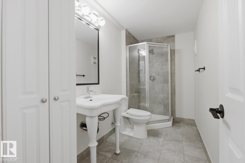 The bathroom features a corner shower with glass enclosure, a pedestal sink, and tiled flooring - 11332 134 Avenue, Edmonton, AB - Indoor Photo Showing Bathroom