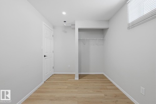 Room featuring light-colored flooring, a white door with dark hardware, and a window with blinds - 11332 134 Avenue, Edmonton, AB - Indoor Photo Showing Other Room