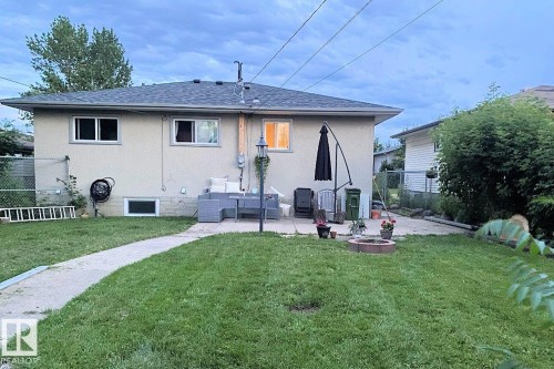 The property features a private yard with a lawn, a paved patio area, and a fire pit - 11332 134 Avenue, Edmonton, AB - Outdoor