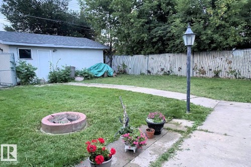 The property features a spacious yard with a lawn, a paved pathway, and a fire pit - 11332 134 Avenue, Edmonton, AB - Outdoor