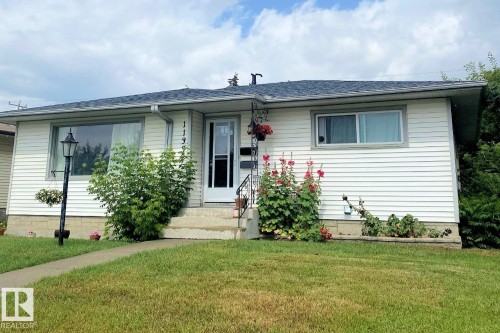 Exterior view of the property featuring white siding, a dark roof, a front lawn, and a sidewalk leading to the front entrance - 11332 134 Avenue, Edmonton, AB - Outdoor