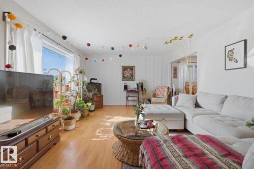 Living room featuring light wood finished floors, plenty of natural light, and a textured ceiling - 11332 134 Avenue, Edmonton, AB - Indoor Photo Showing Living Room