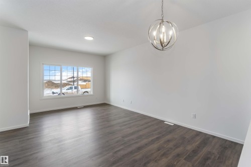 Unfurnished room with hanging lights and dark wood finished floors - 2467 Alces Link Link, Edmonton, AB - Indoor