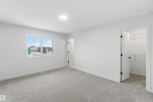 Unfurnished bedroom featuring light colored carpet and a walk in closet - 8652 Edgemont Link Link, Edmonton, AB - Indoor Photo Showing Other Room