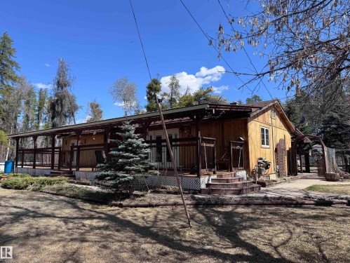 Wood-sided exterior featuring an expansive covered porch with dark wood railings - 59415A Rg Rd 240, Rural Westlock County, AB - Outdoor With Deck Patio Veranda