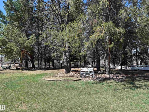 Expansive grassy area featuring mature trees and a stone-lined planter - 59415A Rg Rd 240, Rural Westlock County, AB - Outdoor With View