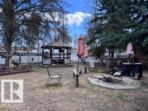 Backyard featuring a built-in gazebo with seating, a stone-surrounded fire pit, and mature trees - 59415A Rg Rd 240, Rural Westlock County, AB - Outdoor With Deck Patio Veranda