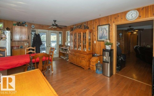 Dining room with ceiling fan, dark wood-type flooring, wood walls, and french doors - 59415A Rg Rd 240, Rural Westlock County, AB - Indoor