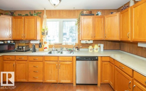 Kitchen featuring stainless steel dishwasher, black microwave, light countertops, wood finish cabinetry, and light wood-type flooring - 59415A Rg Rd 240, Rural Westlock County, AB - Indoor Photo Showing Kitchen With Double Sink