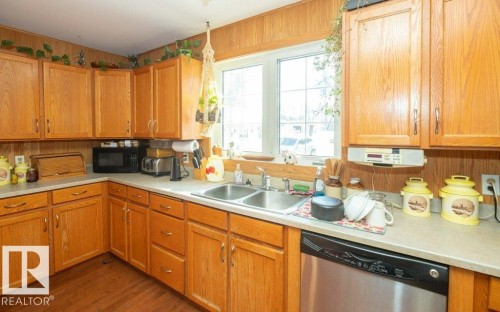 Kitchen with dishwasher, light countertops, black microwave, dark wood-type flooring, and wood finish cabinetry - 59415A Rg Rd 240, Rural Westlock County, AB - Indoor Photo Showing Kitchen With Double Sink