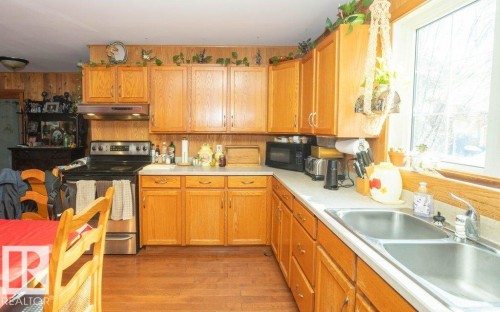 Kitchen featuring electric stove, light countertops, black microwave, and light wood-type flooring - 59415A Rg Rd 240, Rural Westlock County, AB - Indoor Photo Showing Kitchen With Double Sink