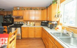 Kitchen featuring electric stove, light countertops, black microwave, and light wood-type flooring - 