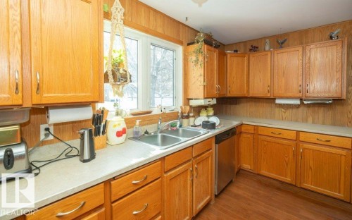 Kitchen with light countertops, dishwasher, wood finished floors, wood finish cabinetry, and wood walls - 59415A Rg Rd 240, Rural Westlock County, AB - Indoor Photo Showing Kitchen With Double Sink