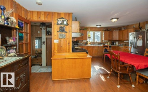 Kitchen with wood walls, stainless steel fridge with ice dispenser, wood finish cabinets, light wood-style floors, and a peninsula - 59415A Rg Rd 240, Rural Westlock County, AB - Indoor