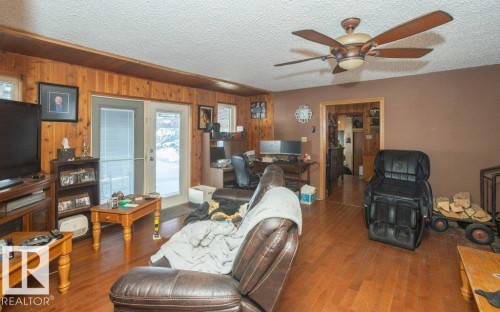 Living room with hardwood / wood-style flooring, a ceiling fan, an office area, a textured ceiling, and french doors - 59415A Rg Rd 240, Rural Westlock County, AB - Indoor Photo Showing Living Room