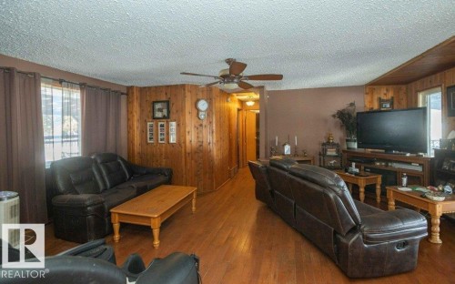 Living area featuring wood walls, a ceiling fan, wood finished floors, and a textured ceiling - 59415A Rg Rd 240, Rural Westlock County, AB - Indoor Photo Showing Living Room