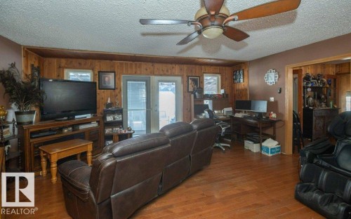 Living room featuring a textured ceiling, wood finished floors, healthy amount of natural light, french doors, and wood walls - 59415A Rg Rd 240, Rural Westlock County, AB - Indoor Photo Showing Other Room