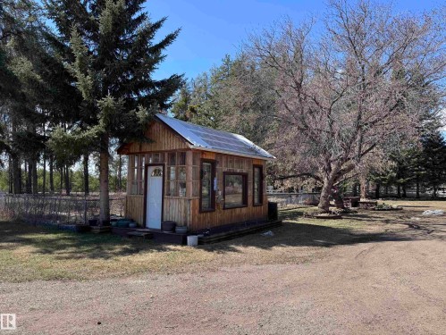 Wood-sided outbuilding featuring multiple windows, a paneled door, and a metal roof - 59415A Rg Rd 240, Rural Westlock County, AB - Outdoor