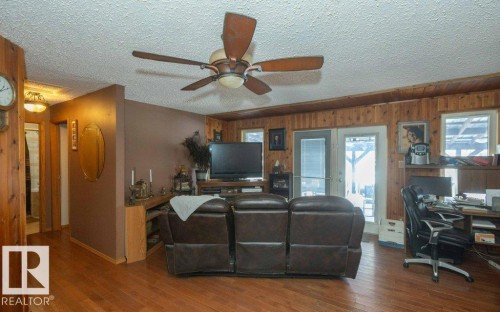 Living area with an office area, a textured ceiling, wooden walls, ceiling fan, and wood finished floors - 59415A Rg Rd 240, Rural Westlock County, AB - Indoor