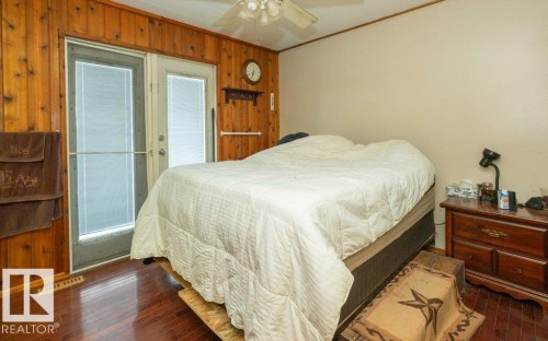 Bedroom featuring dark wood finished floors, wood walls, crown molding, and a ceiling fan - 59415A Rg Rd 240, Rural Westlock County, AB - Indoor Photo Showing Bedroom