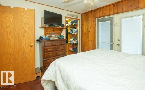 Bedroom featuring a closet, crown molding, a ceiling fan, and wooden walls - 59415A Rg Rd 240, Rural Westlock County, AB - Indoor Photo Showing Bedroom