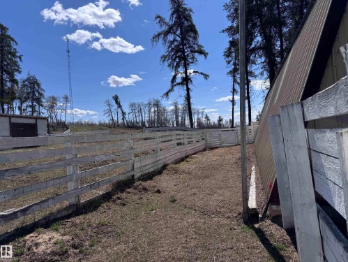 Expansive outdoor area featuring a white wooden fence, a small enclosed structure with a dark window, and a metal-sided building with a sloped roof - 59415A Rg Rd 240, Rural Westlock County, AB - Outdoor With View