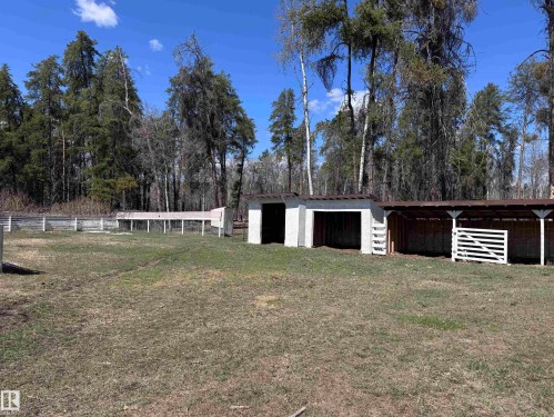 Exterior property featuring multiple shelters, fenced enclosures, and mature trees surrounding a grassy area - 59415A Rg Rd 240, Rural Westlock County, AB - Outdoor