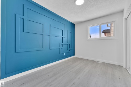 Unfurnished bedroom with a textured ceiling, light wood-type flooring, and a closet - 8635 33 Avenue, Edmonton, AB -  With Exterior