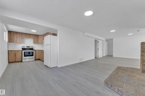 Kitchen with open floor plan, freestanding refrigerator, stainless steel electric stove, light wood-style flooring, and light countertops - 8635 33 Avenue, Edmonton, AB - Indoor Photo Showing Kitchen