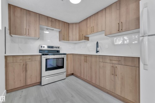Kitchen featuring electric range, freestanding refrigerator, light wood finish cabinets, backsplash, and modern cabinets - 8635 33 Avenue, Edmonton, AB - Indoor Photo Showing Kitchen