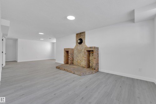 Unfurnished living room with a large fireplace and light wood-type flooring - 8635 33 Avenue, Edmonton, AB - Indoor Photo Showing Other Room