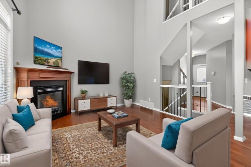 Living area with a fireplace, wood finished floors, and a high ceiling - 11546 11 Avenue, Edmonton, AB - Indoor Photo Showing Living Room With Fireplace