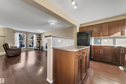 Kitchen with open floor plan, light countertops, backsplash, dark wood-type flooring, and freestanding refrigerator - 6017 213 Street, Edmonton, AB - Indoor Photo Showing Kitchen