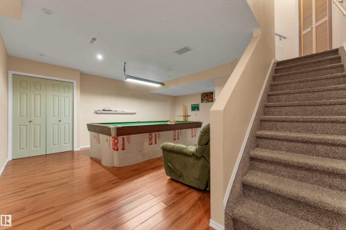 Stairway featuring pool table, wood finished floors, and a textured ceiling - 6017 213 Street, Edmonton, AB - Indoor Photo Showing Other Room