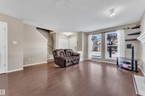 Sitting room with dark wood-style flooring and a textured ceiling - 6017 213 Street, Edmonton, AB - Indoor Photo Showing Living Room