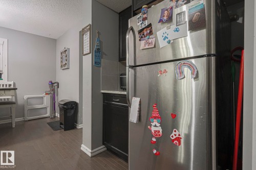 Kitchen featuring freestanding refrigerator, a textured ceiling, dark wood-type flooring, and dark cabinets - 21971 91 Avenue Nw, Edmonton, AB - Indoor
