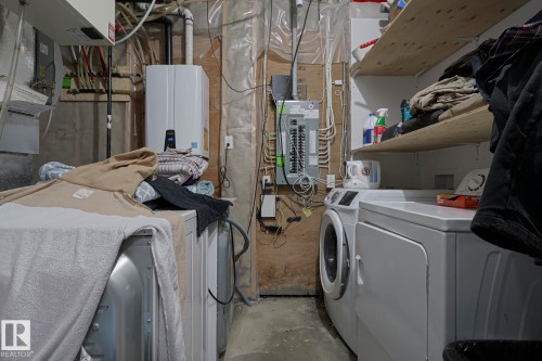 Laundry area featuring concrete floors, washing machine and clothes dryer, electric panel, and tankless water heater - 21971 91 Avenue Nw, Edmonton, AB - Indoor Photo Showing Laundry Room