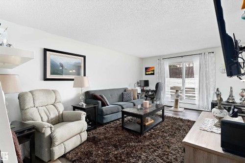 Living area featuring a textured ceiling, a desk, and wood finished floors - # 3 13450 Fort Road, Edmonton, AB - Indoor Photo Showing Living Room